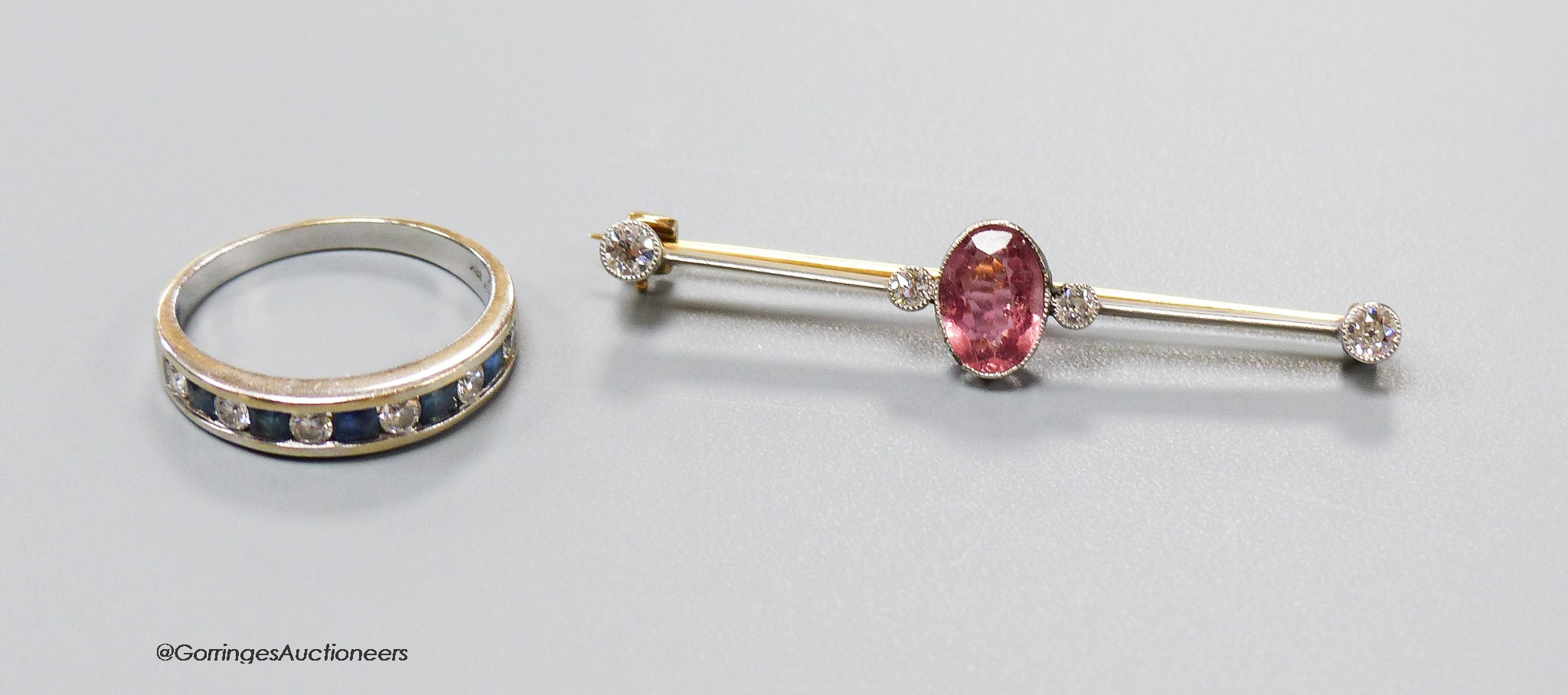 An early 20th century, yellow metal, pink tourmaline and four stone diamond set bar brooch, 47mm, gross 2.7 grams and and 18ct white gold, channel set sapphire and diamond set half eternity ring, size Q, gross 3.9 grams.